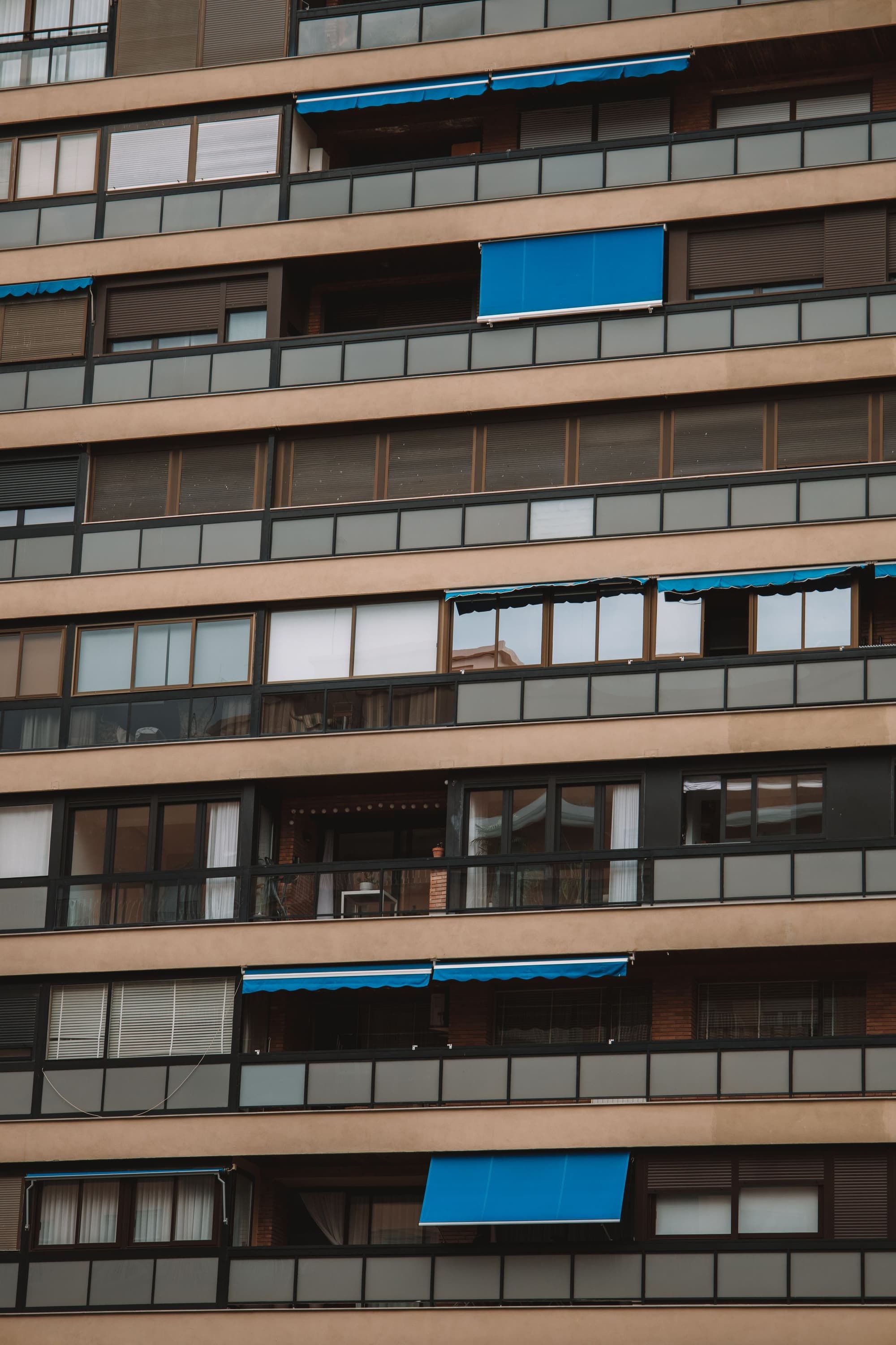 Façana d'un bloc de pisos amb terrasses, persianes i tendals